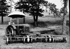 Steel wheel agricultural tractor with traction mower in front.